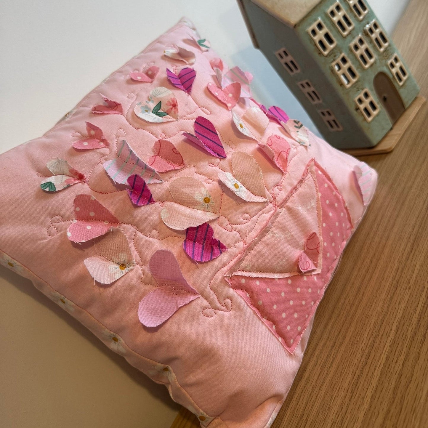 Pink pillow with heart patterns on a wooden surface
